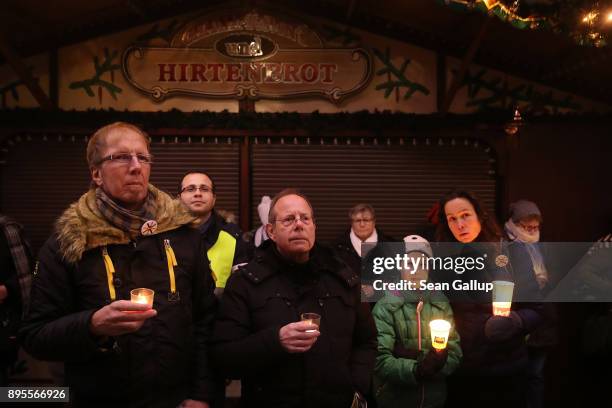 Mourners hold candles as they commemorate the first anniversary of the 2016 Christmas market terror attack at the attack site on December 19, 2017 in...
