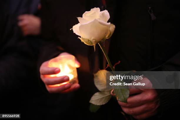 Mourners hold candles and flowers as they commemorate the first anniversary of the 2016 Christmas market terror attack at the attack site on December...