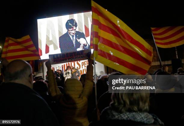 People wave flags and hold banners demanding freedom for jailed separatists leaders as they watch deposed Catalan regional president and 'Junts per...