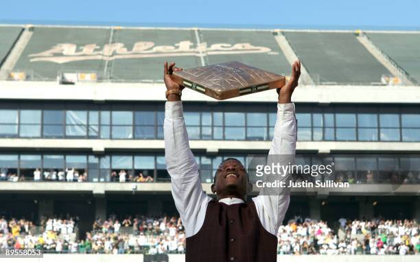 Hall of Fame baseball player Rickey Henderson holds up a golden base during a ceremony to retire his number 24 by the Oakland Athletics before the...