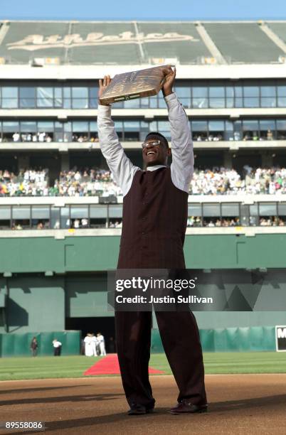 Hall of Fame baseball player Rickey Henderson holds up a golden base during a ceremony to retire his number 24 by the Oakland Athletics before the...