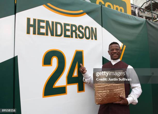 Hall of Fame baseball player Rickey Henderson stands in front of his retired jersey during a ceremony to retire his number 24 by the Oakland...