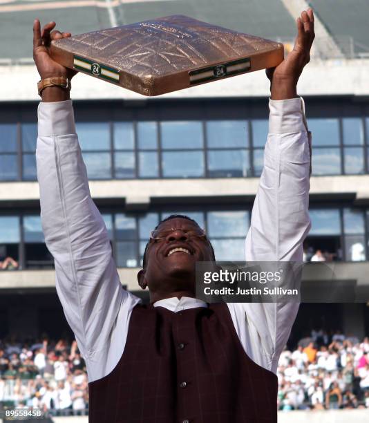 Hall of Fame baseball player Rickey Henderson holds up a golden base during a ceremony to retire his number 24 by the Oakland Athletics before the...