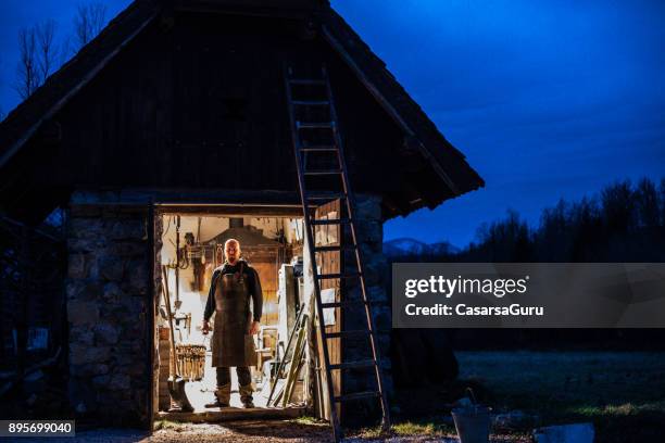 porträtt av smeden och hans smedja på twilight - smedja bildbanksfoton och bilder