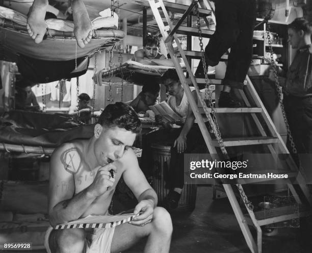 Sailors on the aircraft carrier USS Yorktown catch up on letter writing and reading during off-duty hours, ca. 1943. The ship is operating in...