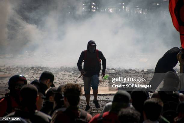 After hurling a rock, a demonstrator turns his back on police and retreats to protest lines. Protestors from various left-wing groups attacked police...