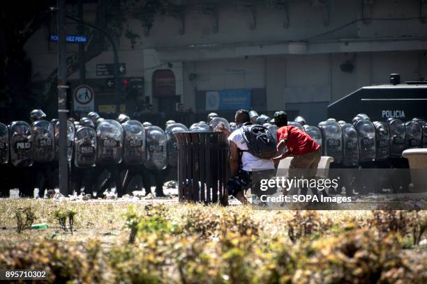 Behind a trashcan, demonstrators take cover from rubber bullets and look for an opportunity to hurl their own projectiles. Protestors from various...