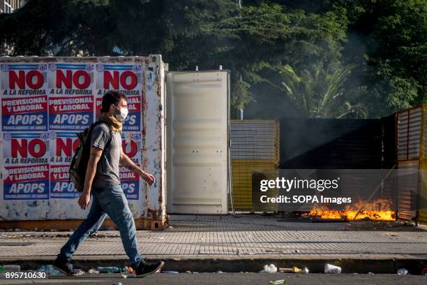 Against a still smoldering fire, a lone protestor advances towards police with posters denouncing the controversial "reforma" that lawmakers are...