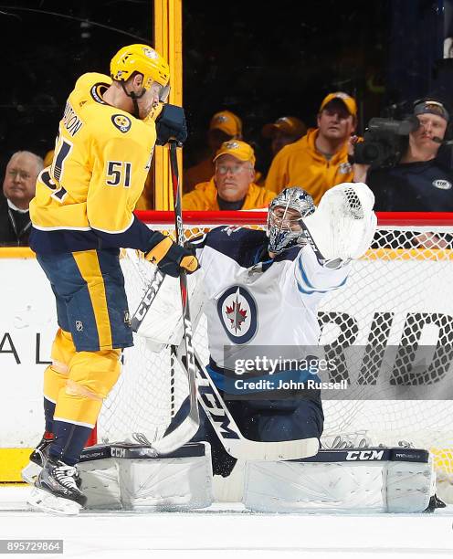 Austin Watson of the Nashville Predators deflects a shot against Connor Hellebuyck of the Winnipeg Jets during an NHL game at Bridgestone Arena on...