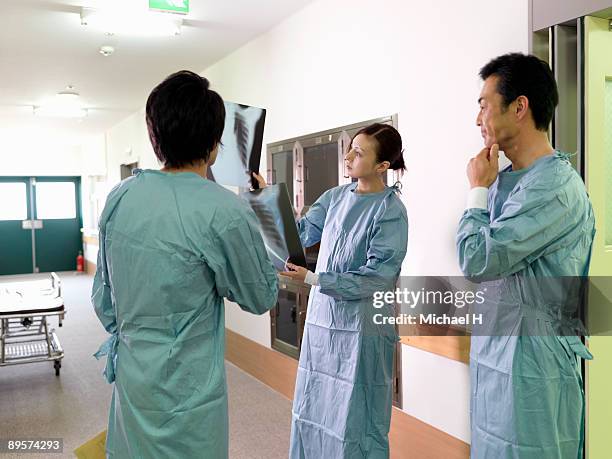 three doctors who see radiograph and discuss it.  - operating gown stock pictures, royalty-free photos & images