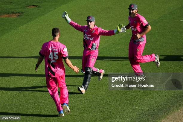 Tim Seifert of the Knights celebrates with teammates Brent Arnel and Dean Brownlie after taking the wicket of Luke Woodcock of the Firebirds to win...