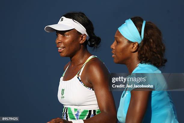 Venus Williams and Serena Williams look on during their doubles match against Yi Chen of Taipei and Mashona Washington during the Bank of the West...