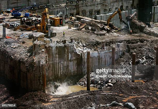 Workers use a backhoe to slowly tear down a mound of concrete and dirt in an area that will become the World Trade Center's transit hub entrance...