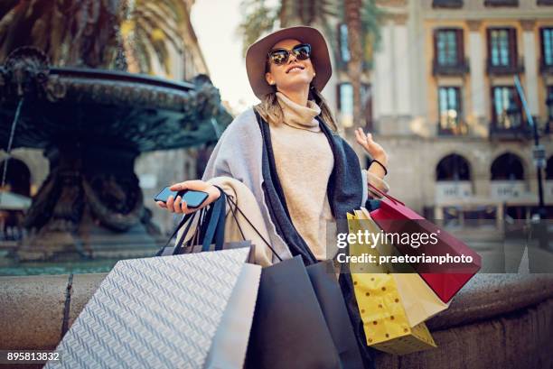 jovem está sentado na fonte, depois das compras - shopaholic - fotografias e filmes do acervo