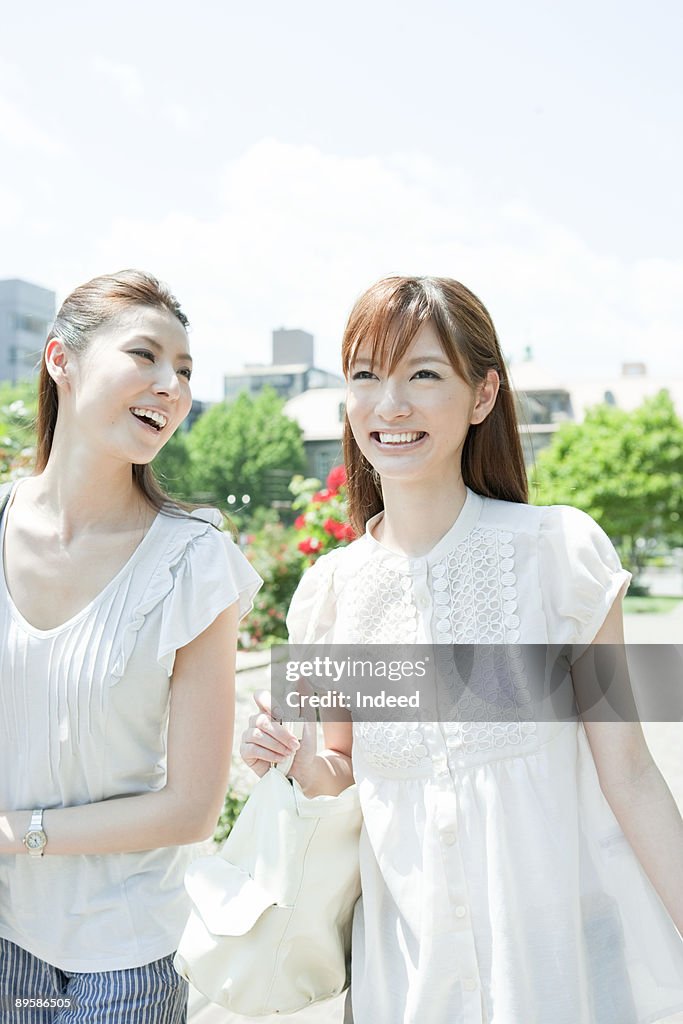 Two young women walking on path, smiling