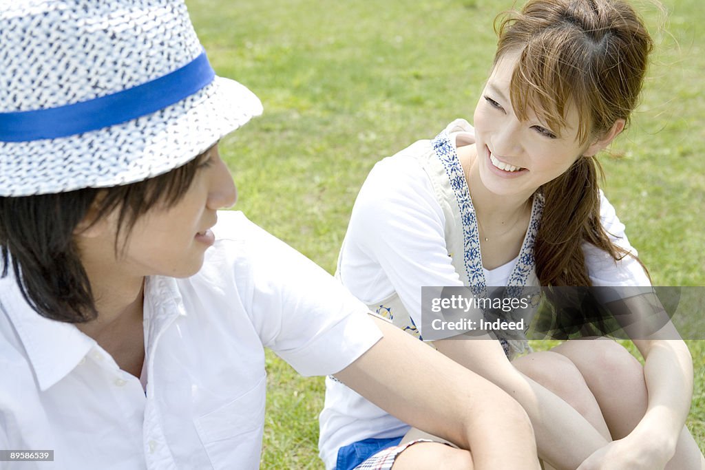Young man and woman smiling face to face on grass