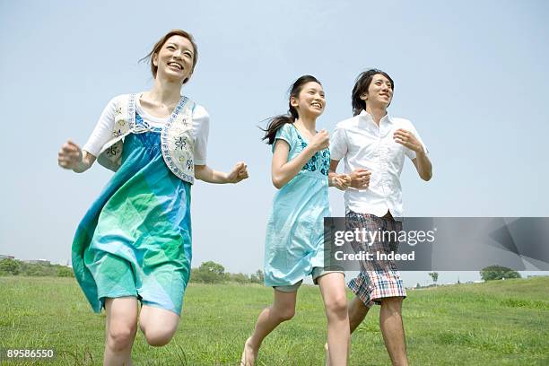 group of friends running on grass, smiling - japan 12 years girl stock pictures, royalty-free photos & images