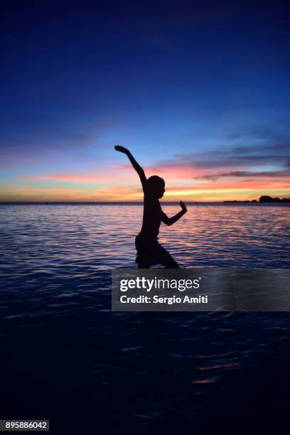 a boy in a cricket bowling action silhouetted against the sunset in palawan island - beach bowl stock pictures, royalty-free photos & images