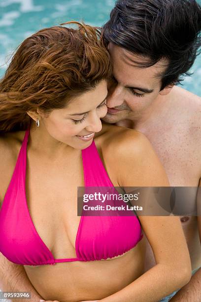 young hispanic couple embracing in pool. - derek latta stock pictures, royalty-free photos & images