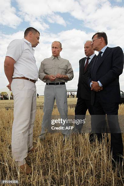 Russian Prime Minister Vladimir Putin speaks with officials during his visit to 'Eksperimentalnoe' farm outside the town of Orenburg on August 4,...