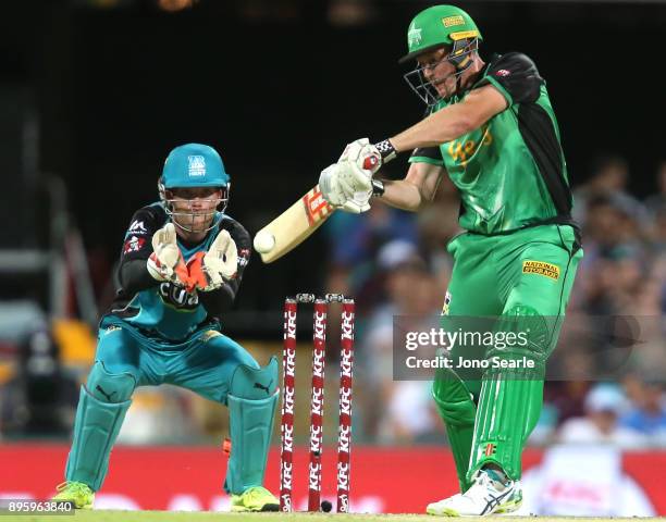 Melbourne Stars player James Faulkner hits the ball as Brisbane keeper Jimmy Peirson looks on during the Big Bash League match between the Brisbane...
