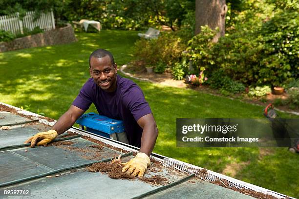 man cleaning gutters - roof gutter stock pictures, royalty-free photos & images