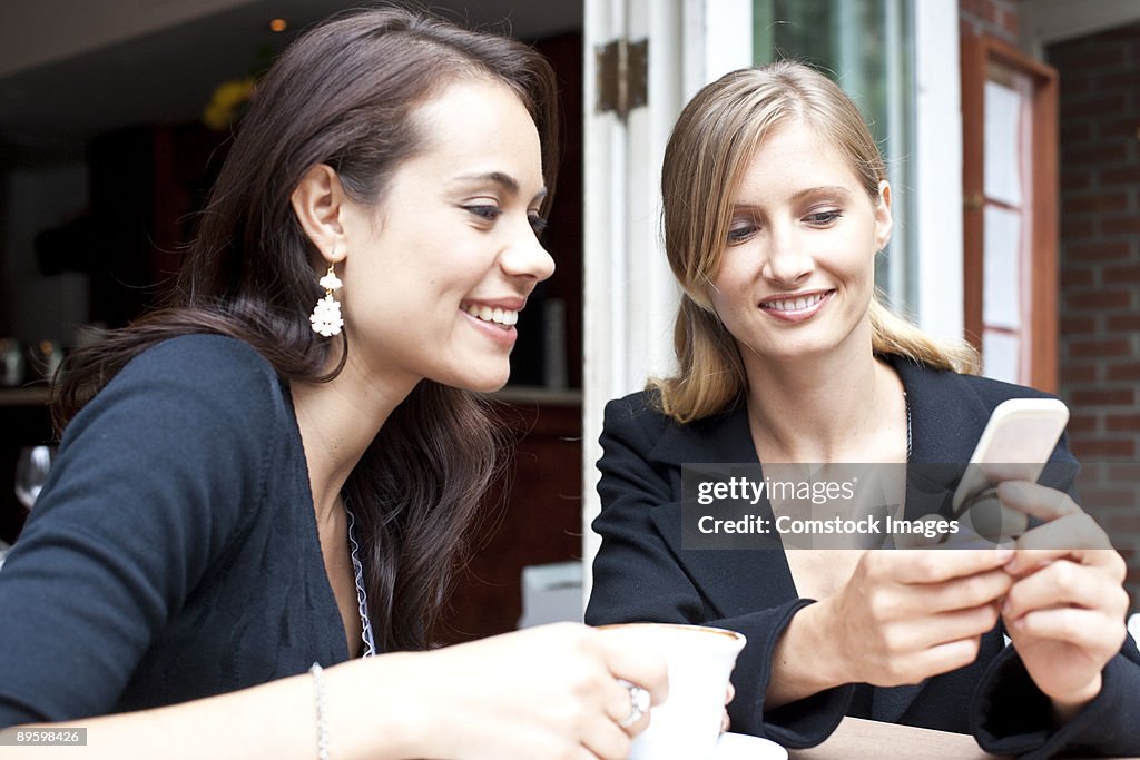 Friends using smart phone at coffee shop