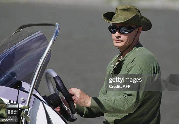 Russian Prime Minister Vladimir Putin drives an outboard motorboat during his vacation outside the town of Kyzyl in Southern Siberia on August 3,...