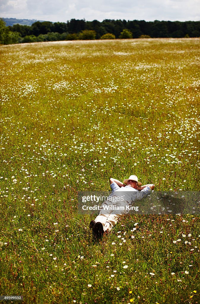 Senior man relaxes lying in a meadow