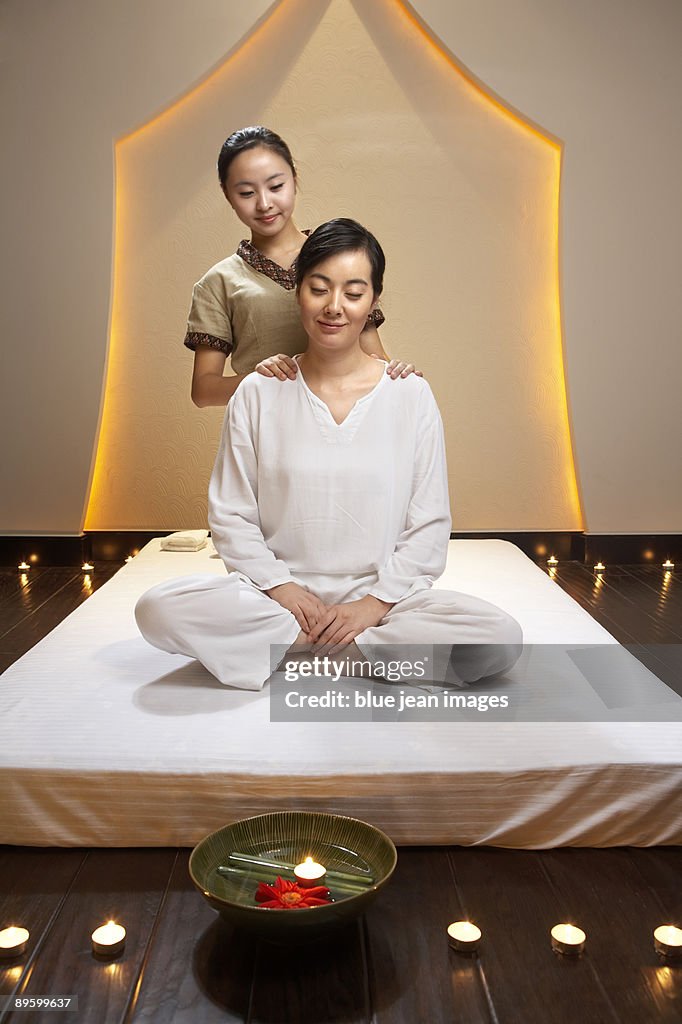 Spa attendant giving a shoulder massage to woman