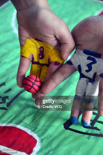 College student volunteers play mini basketball with painted fingers to welcome International Basketball Day at Liaocheng University on December 20,...