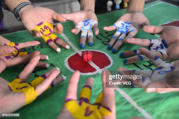 College student volunteers play mini basketball with painted fingers to welcome International Basketball Day at Liaocheng University on December 20,...