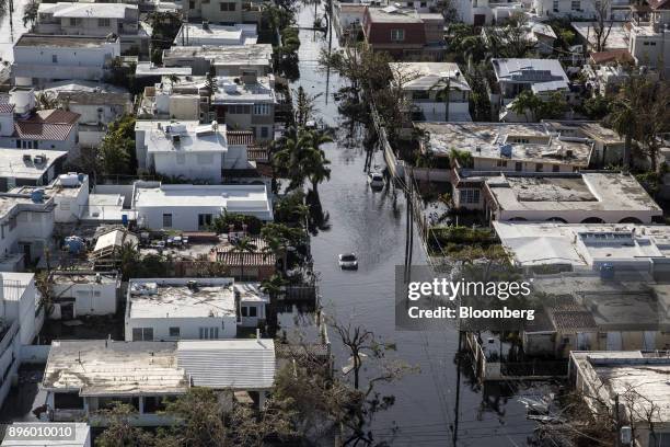 Bloomberg Best of the Year 2017: A vehicle drives through streets filled with floodwater and past destroyed homes caused by Hurricane Maria in this...