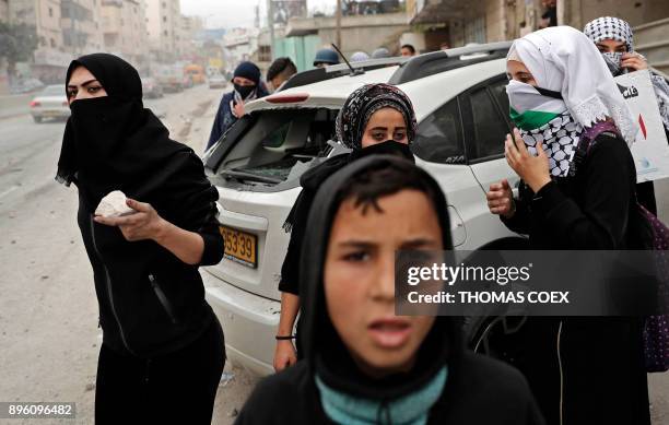 Female Palestinian protestors collect stones to throw towards Israeli security forces during clashes near the Qalandia checkpoint in the Israeli...