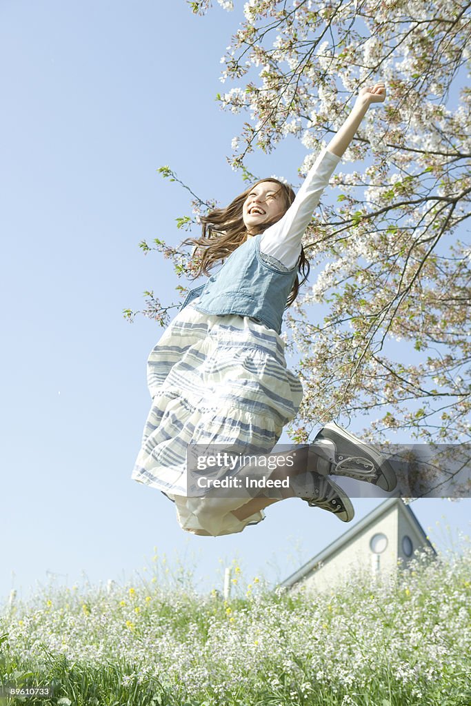 Young woman jumping on flower garden