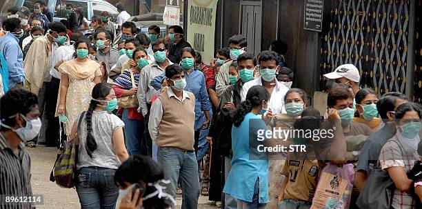 Indians wearing protective masks stand in a queue as they wait to be tested for the A virus - swine flu - at the Naidu hospital in Pune on August 5,...