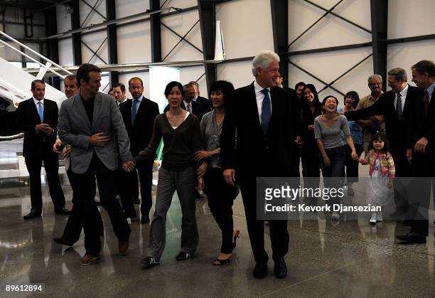 Journalists Laura Ling, husband Iain Clayton and mother Mary Ling walk with former President Bill Clinton as Ling arrives with Euna Lee who is...