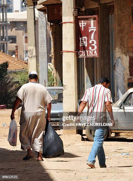 Picture taken on August 5, 2009 shows Algerians walking in front of a Chinese sign at a suburb in Bab Ezzouar, 15 km east of the City center of...