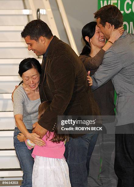 Freed US journalist Euna Lee embraces her husband Michael Saldate and daughter Hana and fellow journalist Laura Ling embraces her husband Iain...