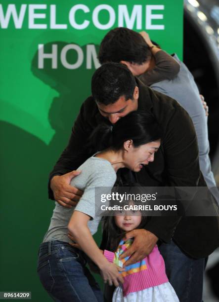 Freed US journalists Laura Ling embraces her husband Iain Clayton, while Euna Lee is welcomed by husband Michael Soldate and daughter Hana after they...