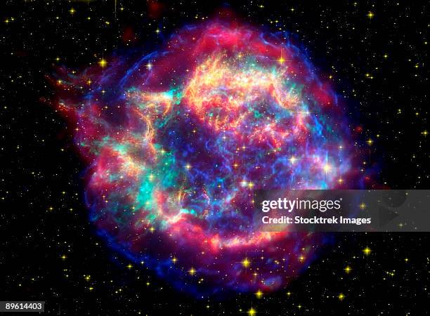 this false-color picture shows off the many sides of the supernova remnant cassiopeia a, which is made up of images taken by three observatories, using three different wavebands of light. - neutrão imagens e fotografias de stock