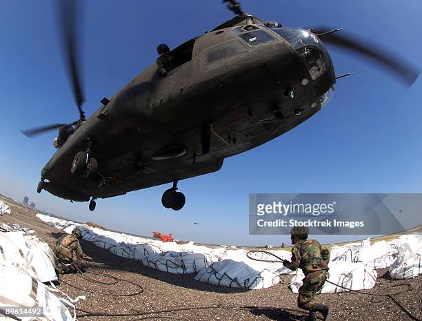 new orleans, louisiana, september 7, 2005 - specialists, both assigned to the army national guard, attach cargo hooks supporting large bags of sand to a ch-47 chinook helicopter.  - sandbag stock pictures, royalty-free photos & images