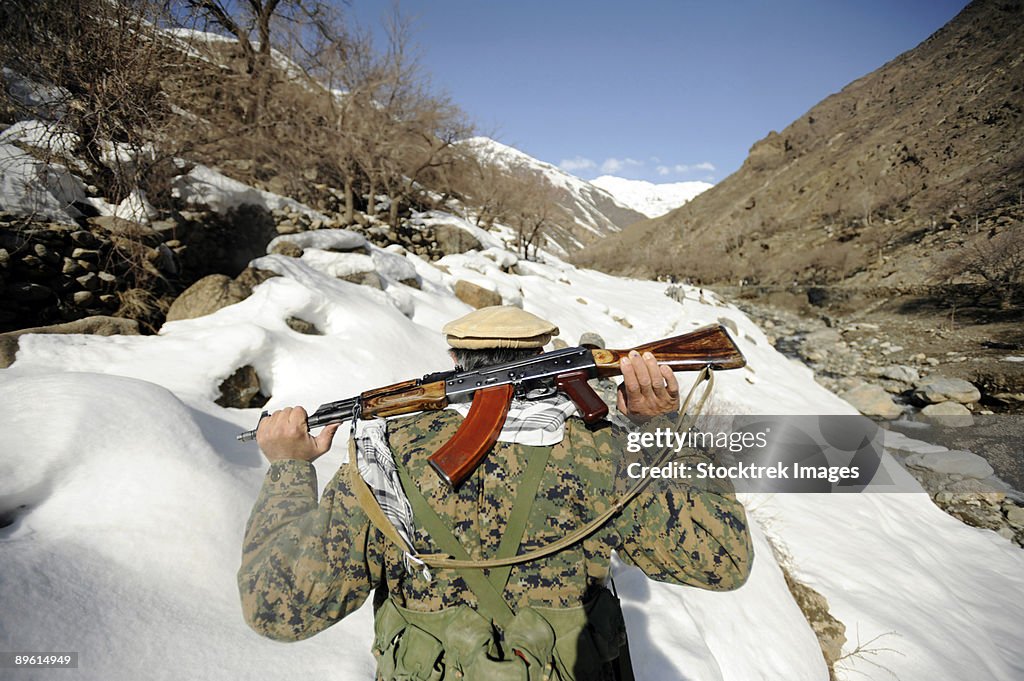 March 5, 2009 - A Mujahideen Guard walks with U.S. Military members of the Afghanistan Panjshir Provincial Reconstruction Team during a site visit in support of Operation Enduring Freedom.