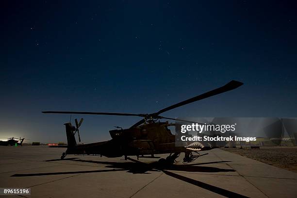 an ah-64 apache waits on the flight line at night at camp speicher. - camp speicher stock pictures, royalty-free photos & images