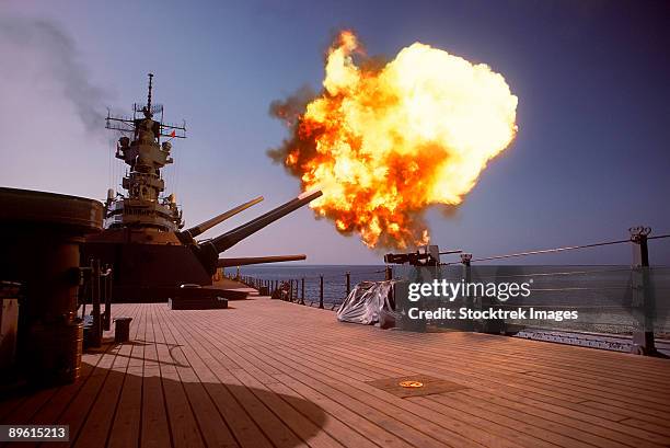 a projectile is fired off the port side from one of the mark 7 16-inch/50-caliber guns in the no. 1 turret aboard the battleship uss wisconsin (bb-64) during a gunnery exercise. the ship is deployed in the gulf to support operation desert shield. - battleship stock pictures, royalty-free photos & images
