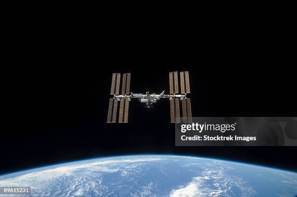 march 25, 2009 - the international space station, backdropped by the blackness of space and earth's horizon. - estação espacial internacional - fotografias e filmes do acervo