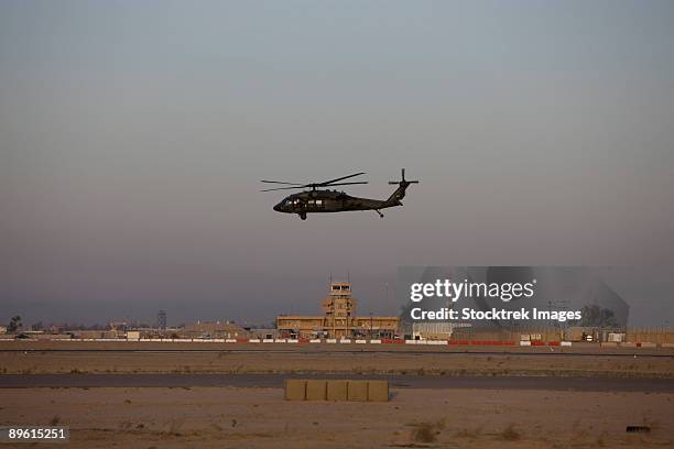 tikrit, iraq - a uh-60 blackhawk helicopter flies past the tower on camp speicher. - camp speicher stockfoto's en -beelden