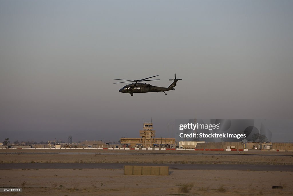 Tikrit, Iraq - A UH-60 Blackhawk helicopter flies past the tower on Camp Speicher.