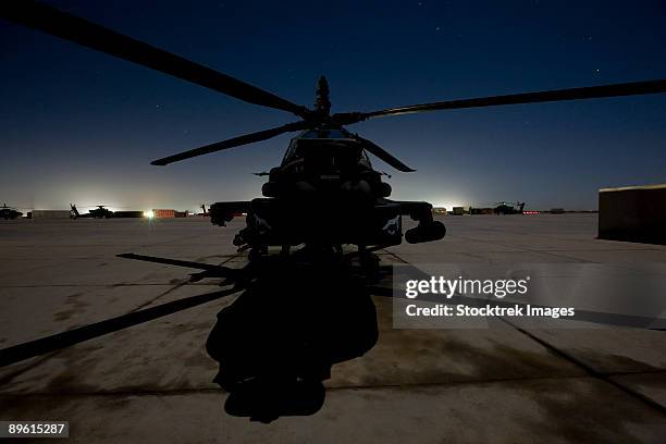 an ah-64 apache waits on the flight line at night at camp speicher. - camp speicher stockfoto's en -beelden