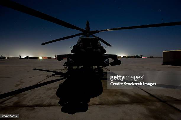 an ah-64 apache waits on the flight line at night at camp speicher. - camp speicher stock pictures, royalty-free photos & images